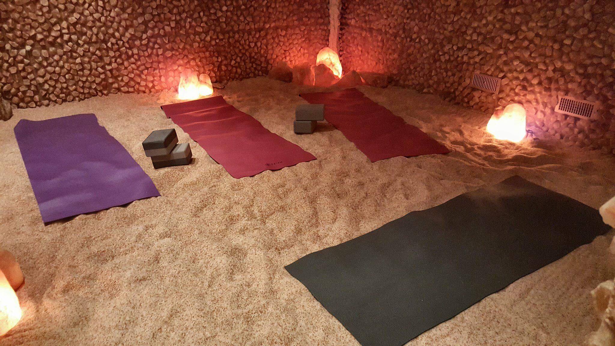Four Yoga Mats On A Salt-Covered Floor With Lighted Himalayan Salt Stone Surrounded By Salt Brick Walls.