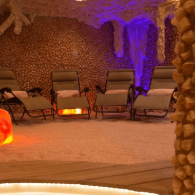 Himalayan Salt Room With Four Reclining Lounge Chairs On A Salt-Covered Floor Surrounded By Himalayan Salt Walls At The Rain Wellness Center.