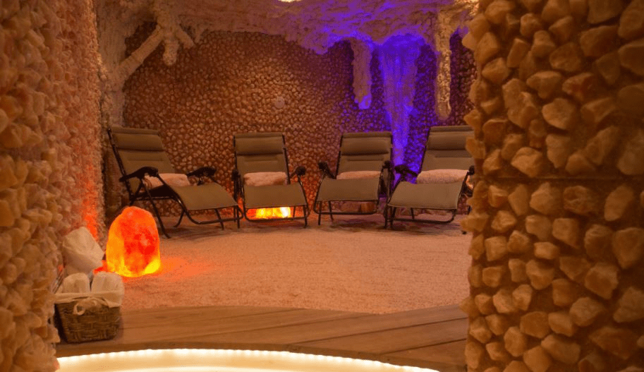 Himalayan Salt Room With Four Reclining Lounge Chairs On A Salt-Covered Floor Surrounded By Himalayan Salt Walls At The Rain Wellness Center.