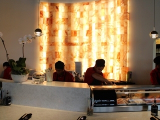 Four Men Making Food In Front Of A Backlit Salt Paneled Wall At The Red Salt Chophouse.