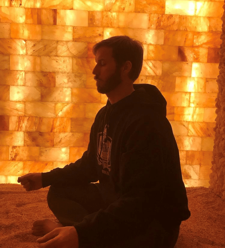 Man Meditating On A Salt Covered Floor In Front Of A Led Backlit Salt Panel Wall At Reflexology By Madalyn - Somerset, Pennsylvania.