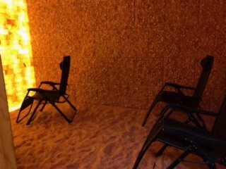Three Reclining Chairs On A Salt-Covered Floor Facing A Led Backlit Salt Panel Wall Surrounded By Salt Brick Walls At Reflexology By Madalyn - Somerset, Pennsylvania.