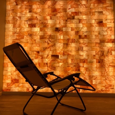 One Reclining Chair On A Wooden Floor In Front Of An Orange Backlit Salt Stone Wall At The Restoring Eden In Gilsum, New Hampshire