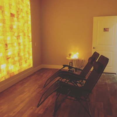 Two Reclining Chairs Facing A Yellow Backlit Salt Stone Wall At The Sage Blossom Massage