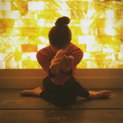 Woman Sitting On A Yoga Mat Doing Yoga In Front Of A Led Backlit Salt Panel Wall At Sage Blossom Massage - Austin, Texas.