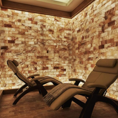 Two Lounge Chairs In A Small Room With Backlit Salt Walls On All Sides