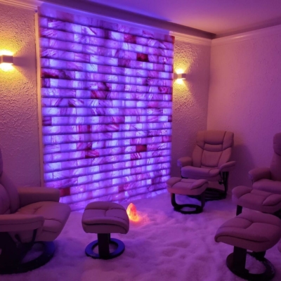 Three Chairs On A Salt Covered Floor Facing A White Backlit Salt Stone Wall At The Salt The Natural Spa In Tampa, Florida