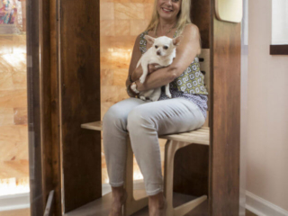 A Smiling Woman Holding A White Dog Receives A Halotherapy Treatment While Sitting In A Salt Booth