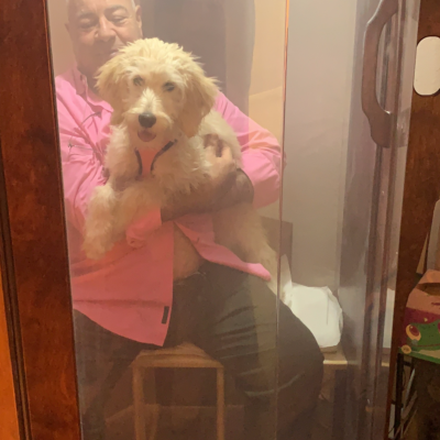 A Man In A Pink Shirt Is Holding A Puppy While They Sit In A Salt Booth Receive A Halotherapy Treatment
