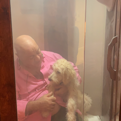 A Man Looks At His Dog While They Both Receive A Halotherapy Treatment While Sitting In A Salt Booth