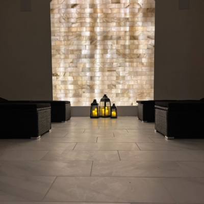 A Beautifully Led Backlit Salt Brick Wall In An Arch Shape With Three Lanterns And Four Black Lounge Benches In A White Marbled-Tiled Room