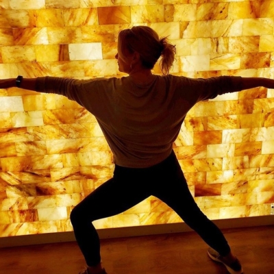 Woman Doing Yoga In Front Of A Led Backlit Salt Panel Wall At Sweet Be Wellness And Skin Clinic Yoga - Greeley, Colorado.