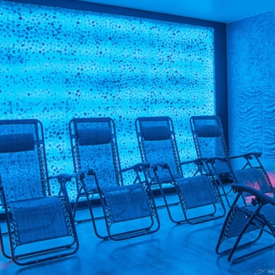 Four Reclining Mesh Chairs In Front Of A White And Blue Backlit Salt Stone Wall At The The Acupuncture Center And Salt Spa
