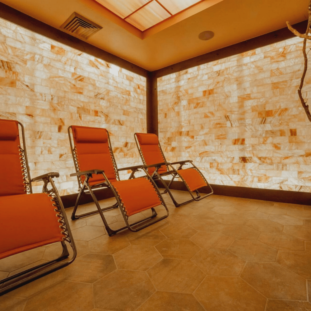 Three Red Chairs Surrounded By Led Backlit Himalayan Salt Panel Walls At The Healing Den Of Salem - Salem, Oregon.