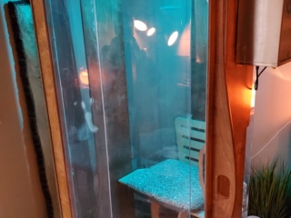An Exterior View Of A Salt Booth With Blue Overhead Lighting And Containers Of Halosalt On The Floor Beside It.