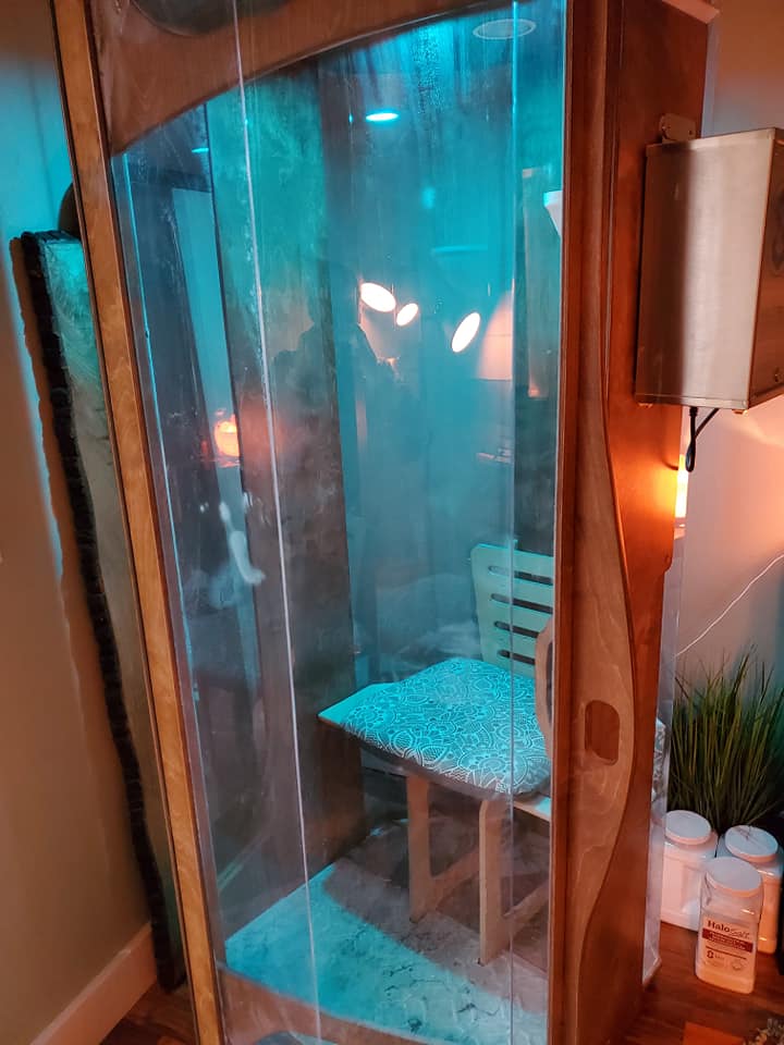 An exterior view of a salt booth with blue overhead lighting and containers of HaloSalt on the floor beside it.