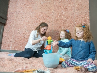A Mother And Her Daughter Play With Floor Salt In A Salt Room Decorated With Salt Panels