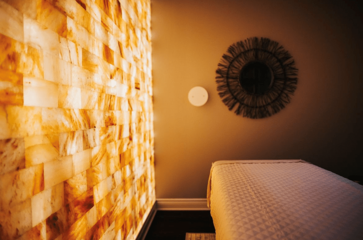 A Salt Therapy Room At The Woodhouse Days Spa In Dallas, Texas With A Massage Table, Himalayan Salt Brick Wall And A Halogenerator On The Wall.