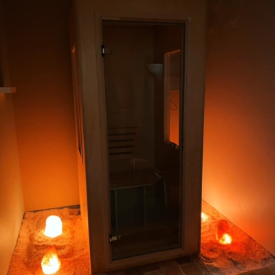 Wooden and glass salt booth on a Himalayan salt stone floor with an almost salt-covered ground and three backlit salt stones on each side.