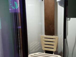 Open Glass Salt Chamber Booth With A White Chair Inside.