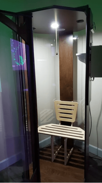 Open glass salt chamber booth with a white chair inside.