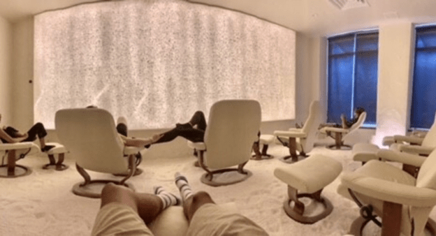 Guests Relaxing In Lounge Chairs And Enjoying A Salt Therapy Treatment In A Room With A Salt Wall And Salt Floor