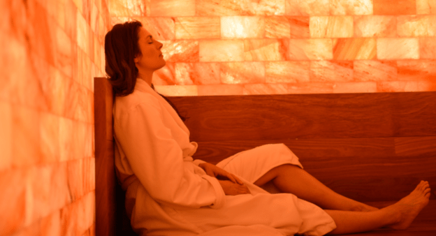 A Woman Sitting On A Bench In A Salt Therapy Room.