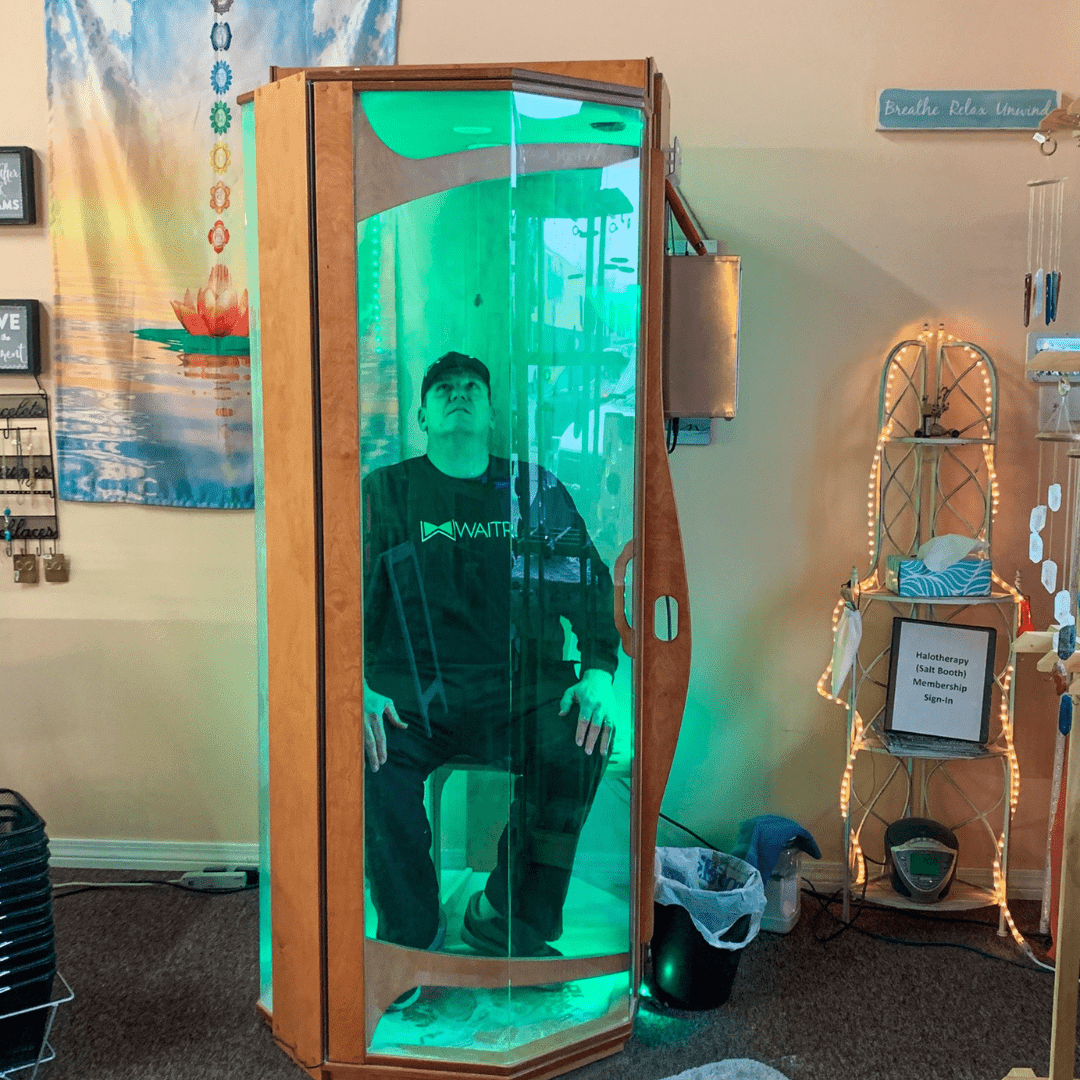 A man sitting in an Original SALT Booth for a salt therapy session at Mystic Bayou Holistic and Alternative Health.
