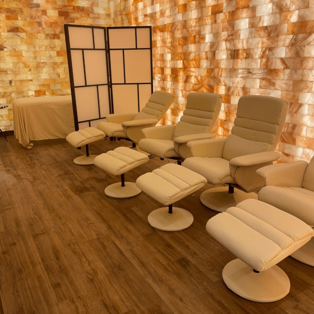 The salt room at Vitalie with 4 chairs, a massage table and Himalayan salt brick walls.