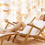 A Woman Laying In A Chair In A Salt Room With Himalayan Salt Bricks On The Wall.