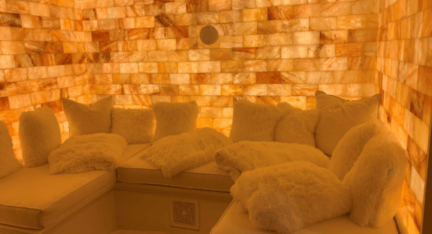 A salt room at a private residence with seats, Himalayan salt bricks and a halogenerator on the wall.