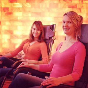 Image Of Two Women Enjoying A Salt Therapy Session In A Salt Room With Himalayan Salt Bricks On The Wall. | Salt Chamber
